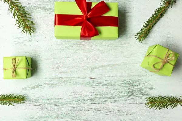 Vánoční kompozice. Tři zelené dary, smrkové větve, na lehkém dřevěném pozadí. Vánoce, zima, novoroční koncept. Byt ležel, horní pohled, kopírovací prostor — Stock fotografie