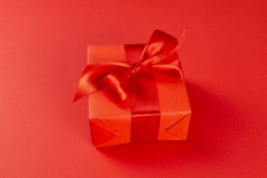 Noel kompozisyonu. Kırmızı arka planda kırmızı kurdeleli kırmızı hediye kutusu. Yukarıdan bak. Noel hediyesi.