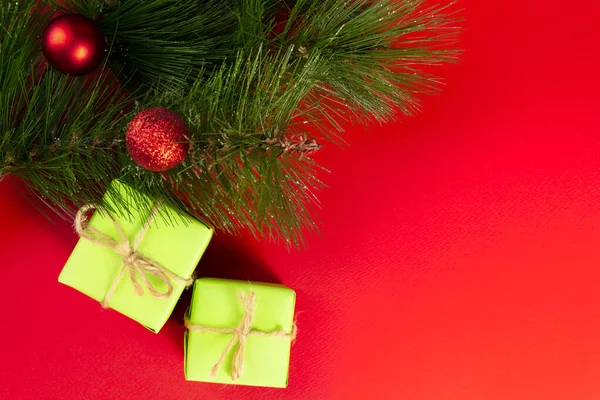 Vánoční kompozice. Zelené dárkové krabice pod vánoční stromeček na červeném pozadí. Pohled shora. Vánoční dárek — Stock fotografie