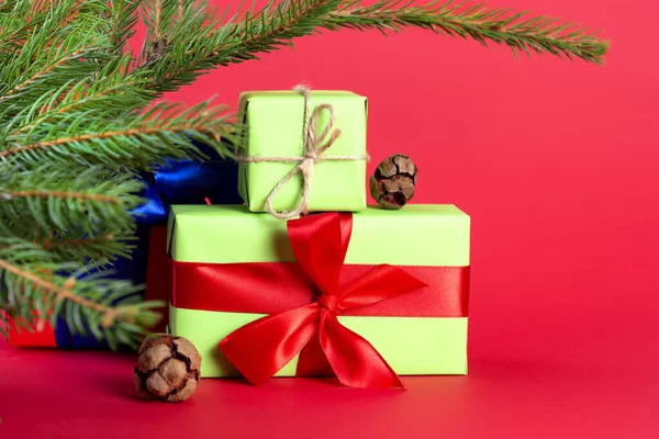 Vánoční kompozice. Zelené dárkové krabice pod vánoční stromeček na červeném pozadí. Vánoční dárek — Stock fotografie