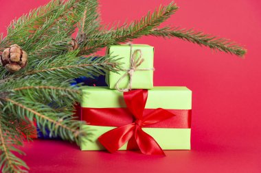 Noel kompozisyonu. Noel ağacının altındaki yeşil hediye kutusu kırmızı arka plan yakınındaki ahşap bir masada. Noel hediyesi.