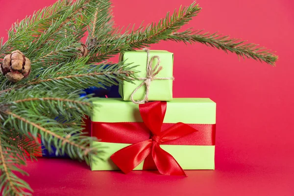 Świąteczna kompozycja. Zielone pudełko pod choinką na drewnianym stole w pobliżu czerwonego tła. prezent świąteczny — Zdjęcie stockowe