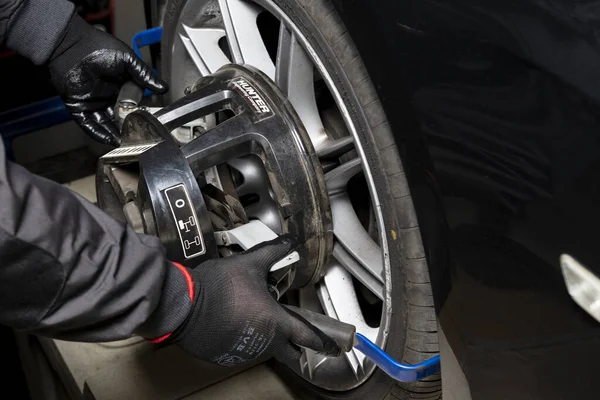 Minsk, Belarus, 1 Mayıs 2019. Bir araba tekerleğinde tekerlek hizalama ekipmanı. Bir tamircinin elleri tekerlekte bir aygıt takar
