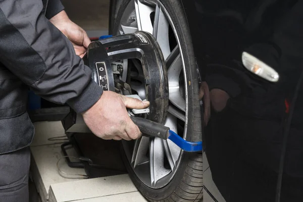 Minsk, Belarus, 1 Mayıs 2019. Bir araba tekerleğinde tekerlek hizalama ekipmanı. Bir tamircinin elleri tekerlekte bir aygıt takar