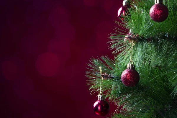 Zbliżenie Boże Narodzenie dekoracje noworoczne, gałązki jodły z błyszczących zabawek wakacyjnych, czerwone kulki na czerwonym tle z pasemkami — Zdjęcie stockowe