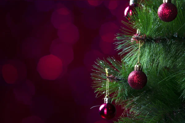 Boże Narodzenie sosna gałąź z czerwonymi kulkami zbliżenie na czerwonym tle — Zdjęcie stockowe