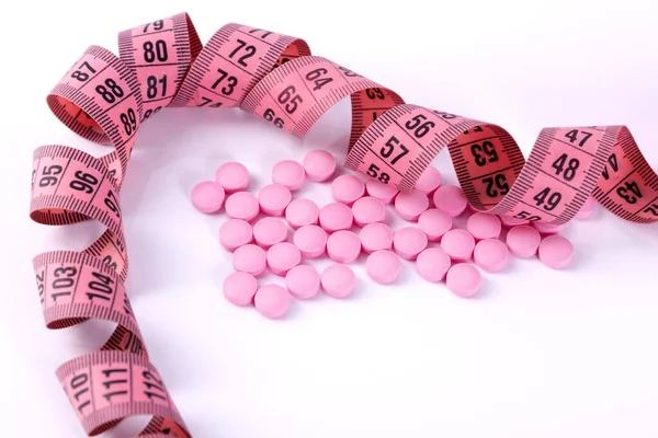 Comprimidos com uma fita métrica para representar a indústria de pílulas de dieta — Fotografia de Stock