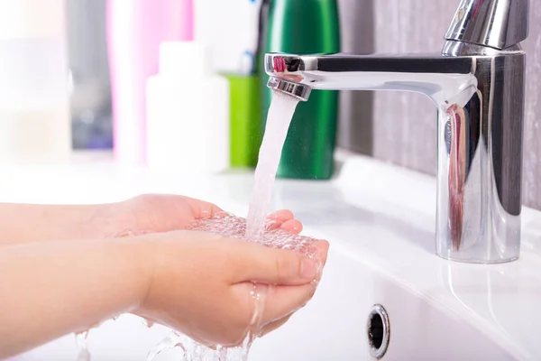 Washing of children\'s hands with soap under the crane with water.