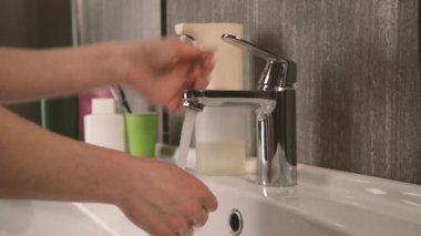 Dişi eller, deriyi virüslerden arındırmak için ellerini lavaboda yıkar..