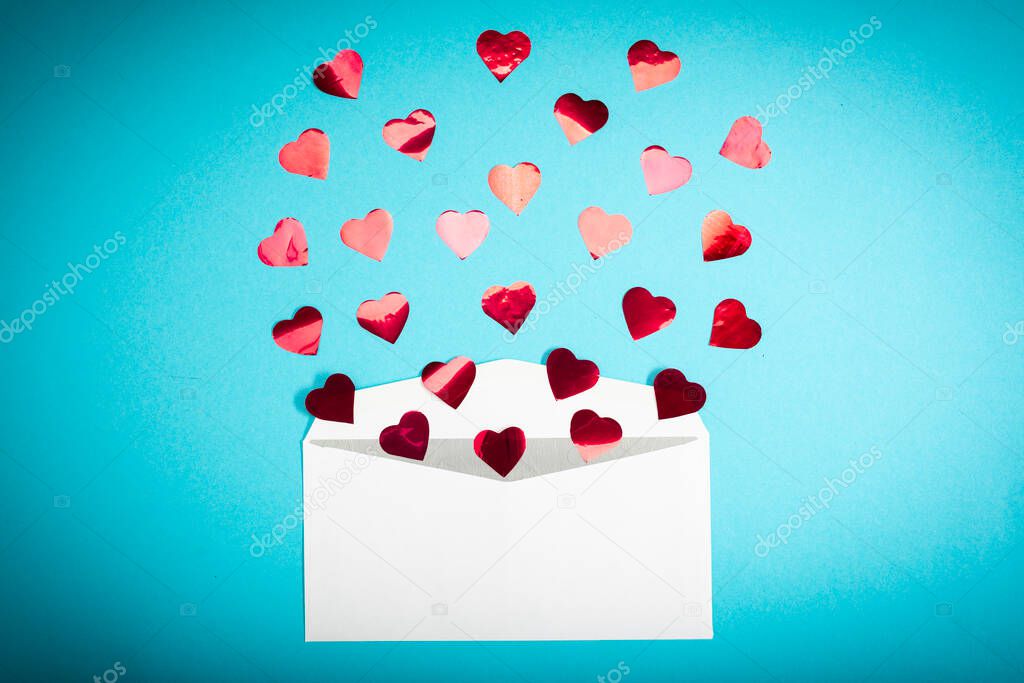 Red confetti hearts fly out of a white envelope on a light blue background. Valentines Day. love concept Gift, message for lover
