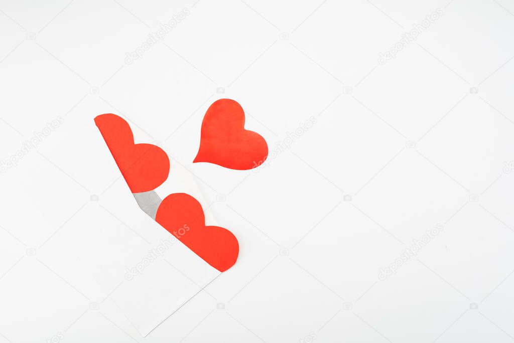 Open envelope and three red paper hearts on a white background with place for text