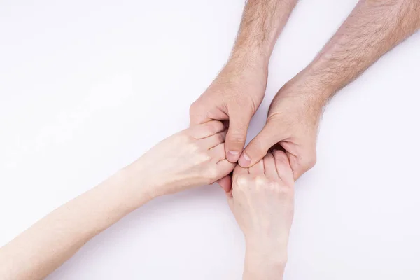 Женские руки в руках мужчин лежат на белом фоне. Мужчина и женщина держатся за руки, отношения, брак, предложение — стоковое фото
