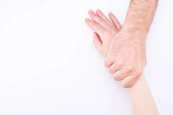 Concepto de violencia doméstica. El hombre tira de una mano de mujer sobre un fondo blanco — Foto de Stock