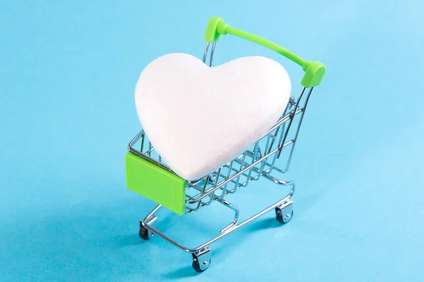 Cuore bianco nei cestini della spesa su sfondo blu. Comprare amore, comprare un cuore — Foto Stock