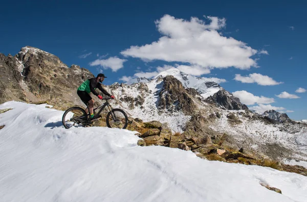 山の雪の中でマウンテン バイクに乗ってのサイクリスト — ストック写真