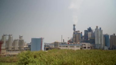 boru ve tanklar duman ile fabrika boru geliyor, ağaçlar yakın büyümek