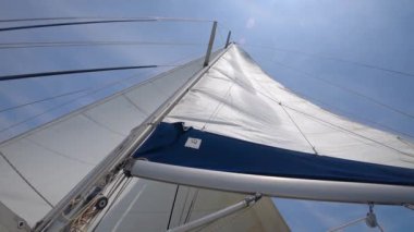 Yat alt görünümünde doğrultulan yelken, gökyüzü direğinde görünür bulutlar