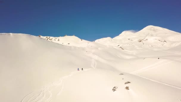 Luftbild der schneebedeckten Berge, darunter zwei Snowboarder — Stockvideo