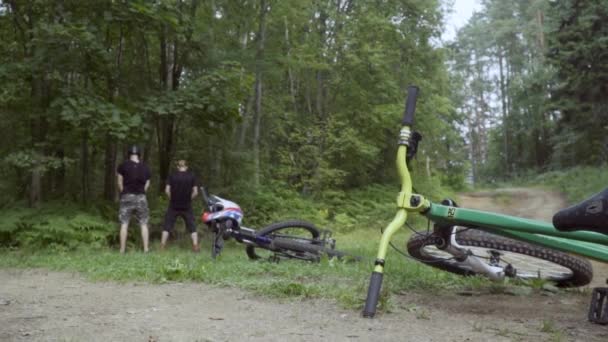 Két kerékpáros húgy a bokrok az előtérben a kerékpárok — Stock videók