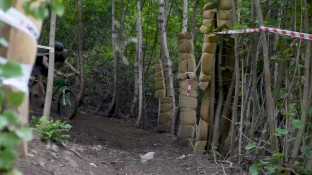 Cycliste sur un vélo vert descend le long d'un chemin de terre vers le bas, entouré d'arbres — Video