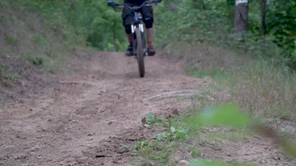 Два велосипедиста едут по лесной дороге, грязь вылетает из-под колес — стоковое видео
