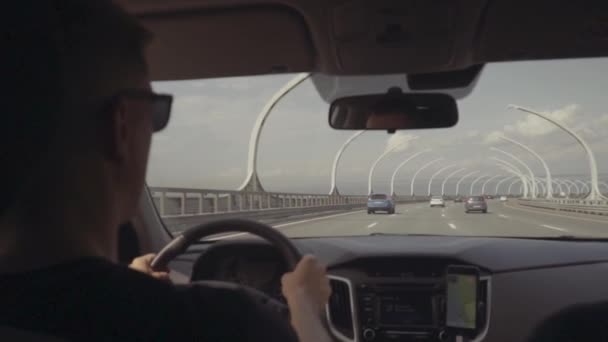 Seorang pria berkacamata hitam mengendarai jembatan di atas mobil — Stok Video