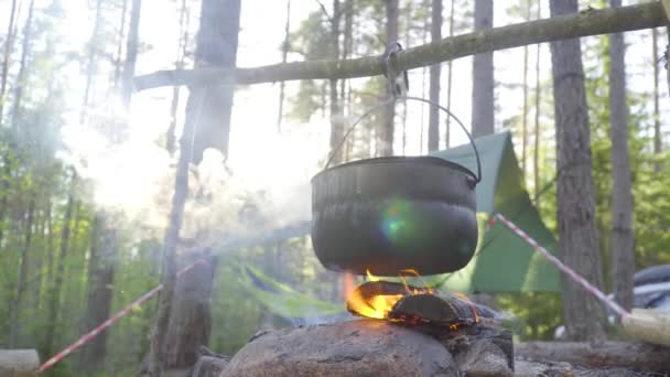Ein Topf, der an einem Stock über dem Feuer hing, das Feuer, das es umhüllte — Stockvideo