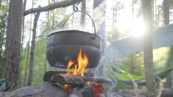 Garnek wiszący na patyku nad ogniem, ogień owinięty wokół niego — Wideo stockowe