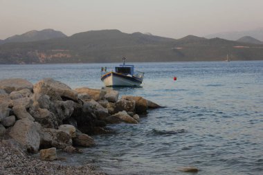 Küçük ahşap balıkçı teknesi kayalık sahil yakınında demirledi. Lefkada Adası, Yunanistan.