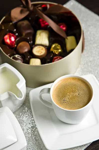Still life of a cup of coffee and box of chocolates.