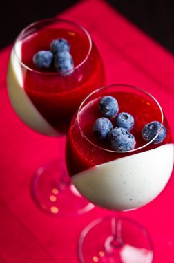 Çilek mus ve krem lezzetli panna cotta tatlı şarap bardaklarda servis. Kırmızı ve beyaz çapraz yaratıcı kompozisyon.