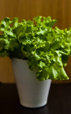 Ahşap kesme tahtası arka plan beyaz bir tencerede taze organik salata.