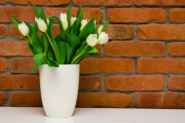 Fehér tulipán Csokor vázában, vörös téglafal ellen. — Stock Fotó