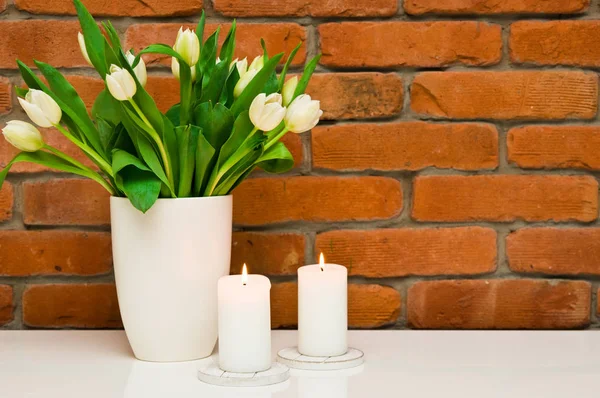Букет білих тюльпанів у вазі на стіні з червоної цегли . — стокове фото