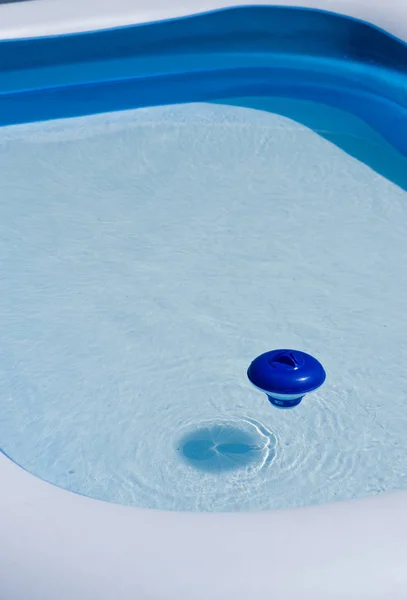 Dispensador de cloro plástico azul flotando en la superficie del agua —  Fotos de Stock