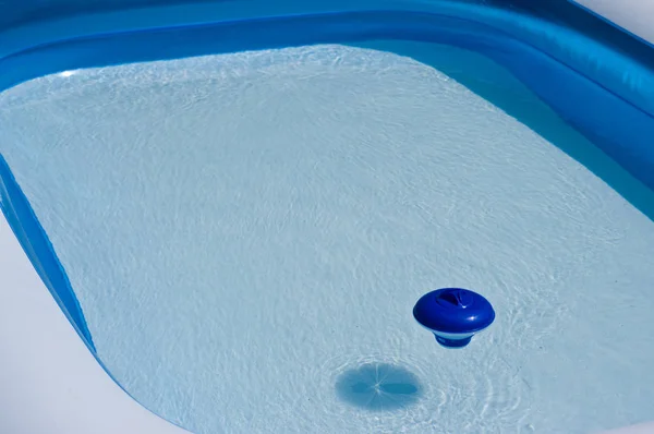 Blue plastic chlorine dispenser floating on the surface of water