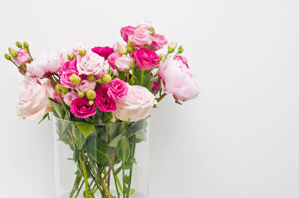 Bouquet of pink roses, peony flowers in glass vase on a shelf ag