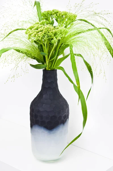 Zelené travnaté a polní květiny v moderní onyxové váze na polici. — Stock fotografie