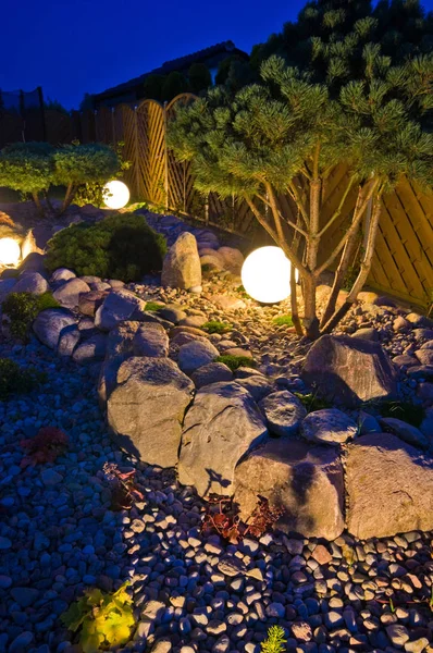 Home garden at night, illuminated by globe shaped lights