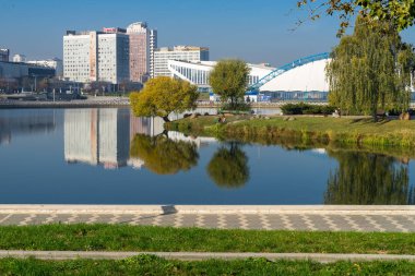 Minsk, Beyaz Rusya - 14 Ekim 2018: Svisloch Nehri - mevsimsel buz pateni pisti hava kubbe, Minsk Spor Sarayı ve çok öykülü evleri su yansımalar görünümüyle