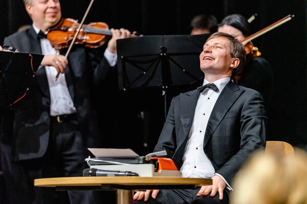 ВИЛНИУС, ЛИТУАНИЯ - 24 февраля 2019 года: Международная Вильнюсская книжная ярмарка. Играет Камерный оркестр при мэрии Вильнюса. Спереди - главный дирижер М.Баркаускас
