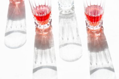 Dört gözlük güneş önce. Onların gölgeler beyaz zemin üzerine yansıtılır. Üç bardak kırmızı suyu vardır