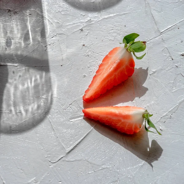 Two slices of strawberries and a glass shadow before the sun.