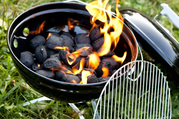 The charcoal in the grill is on fire and the flames are orange.