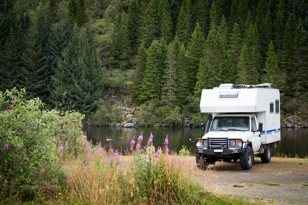 A large four wheel camper car parked nearby the water in beautiful nature. Лофотенские острова, Норвегия.