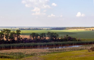 Mavi gökyüzündeki tepeden güzel bir manzara, ufuktan uzanan nehir ve tarım alanları..