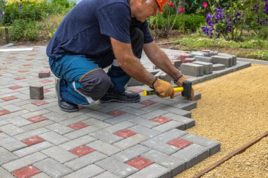 Profesyonel tuğla ustaları yol, kaldırım ya da veranda için yeni kiremitler ya da levhalar döşüyorlar. Evin avlusuna gri beton döşeme döşemesi.