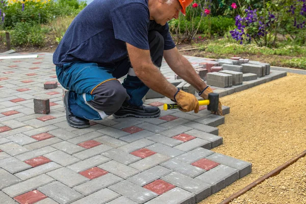 Profesyonel tuğla ustaları yol, kaldırım ya da veranda için yeni kiremitler ya da levhalar döşüyorlar. Evin avlusuna gri beton döşeme döşemesi.