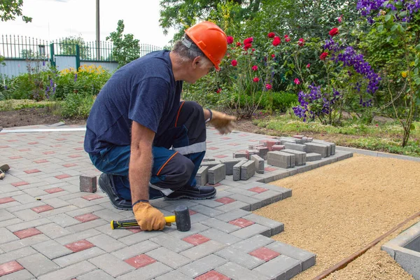 Profesyonel tuğla ustaları yol, kaldırım ya da veranda için yeni kiremitler ya da levhalar döşüyorlar. Evin avlusuna gri beton döşeme döşemesi.