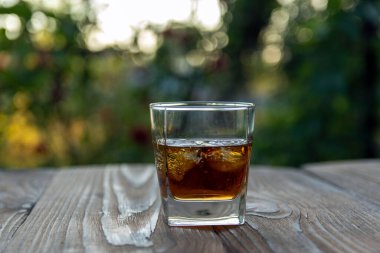 Kokulu viski, kırsal bir evin bahçesindeki eski bir bahçe masasında. Seçici odak